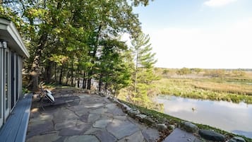 Sit on the stone patio and enjoy the serene views of the calm body of water surrounded by lush greenery.