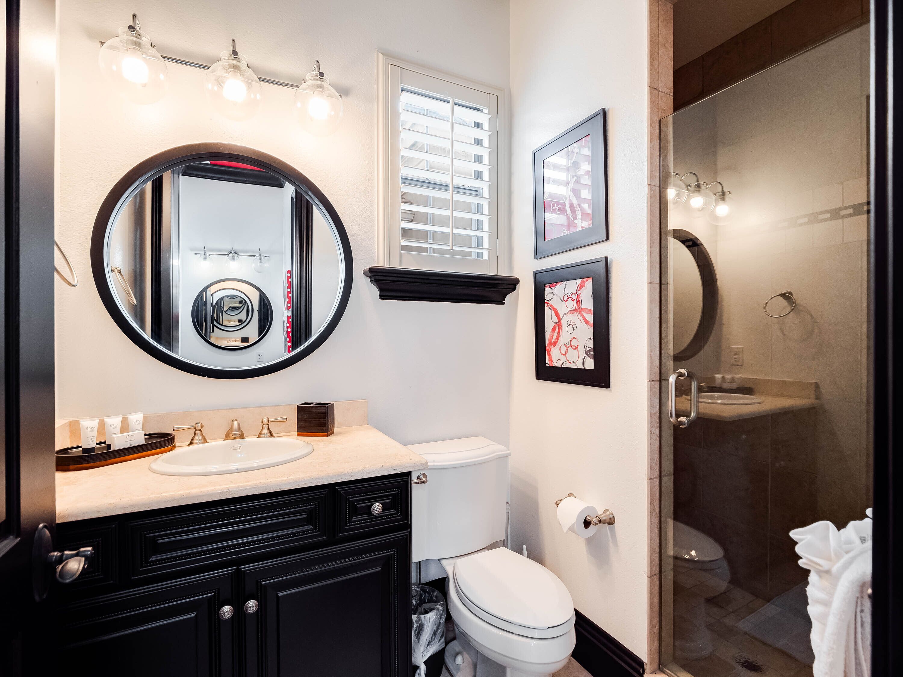 A modern bathroom with a round mirror, a toilet, a sink, and a shower area.
