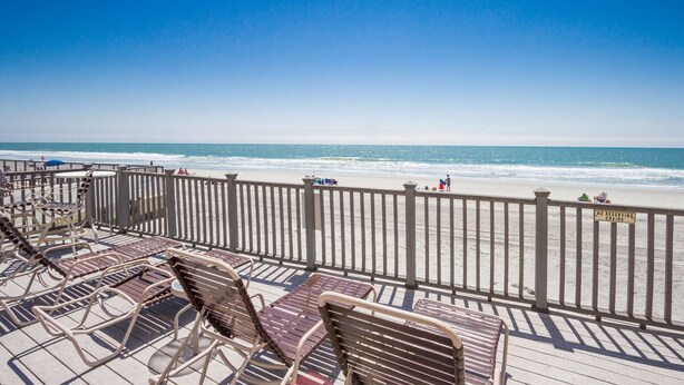A beach view from a wooden deck with metal chairs and a railing. - *Fall into Savings-20% Off New Bookings thru 2026* (Garden City)