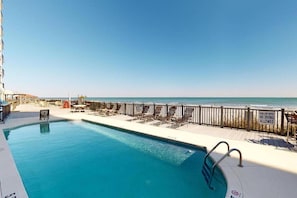 A pool area with a view of the ocean, a lifeguard stand, and a sign indicating no diving allowed.