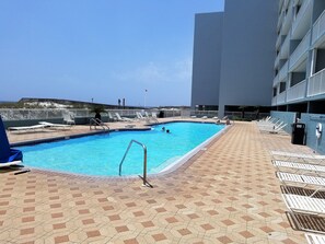 Une piscine avec des chaises longues et une terrasse carrelée.