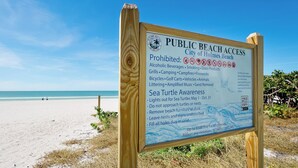 Letrero de acceso público a la playa con indicaciones y datos sobre la conservación de tortugas marinas.