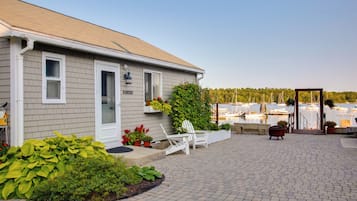 Enjoy a scenic view of the marina from this property's patio, featuring a brick floor and a charming porch with a chair and potted plant.