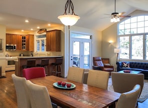 Una cocina moderna con armarios de madera, una isla central y un comedor con mesa y sillas de madera.