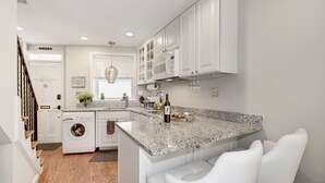 A modern kitchen with white cabinetry, a granite countertop, and a built-in washing machine.