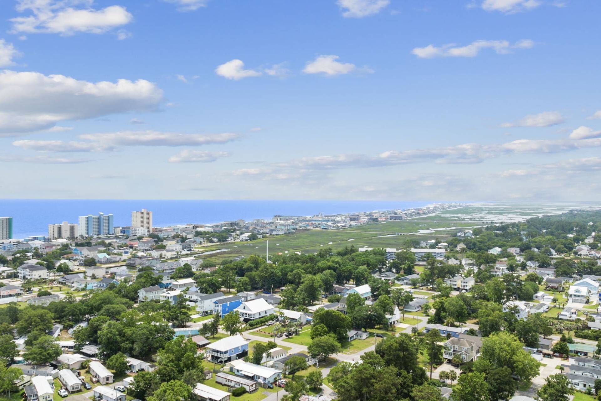 A residential area with houses, some with attached garages, and a distant view of a coastline.