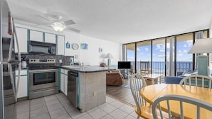 A modern kitchen with a central island, a dining area with a view of the ocean, and a balcony with a table and chairs. - *Fall into Savings-20% Off New Bookings thru 2026* (Murrells Inlet)