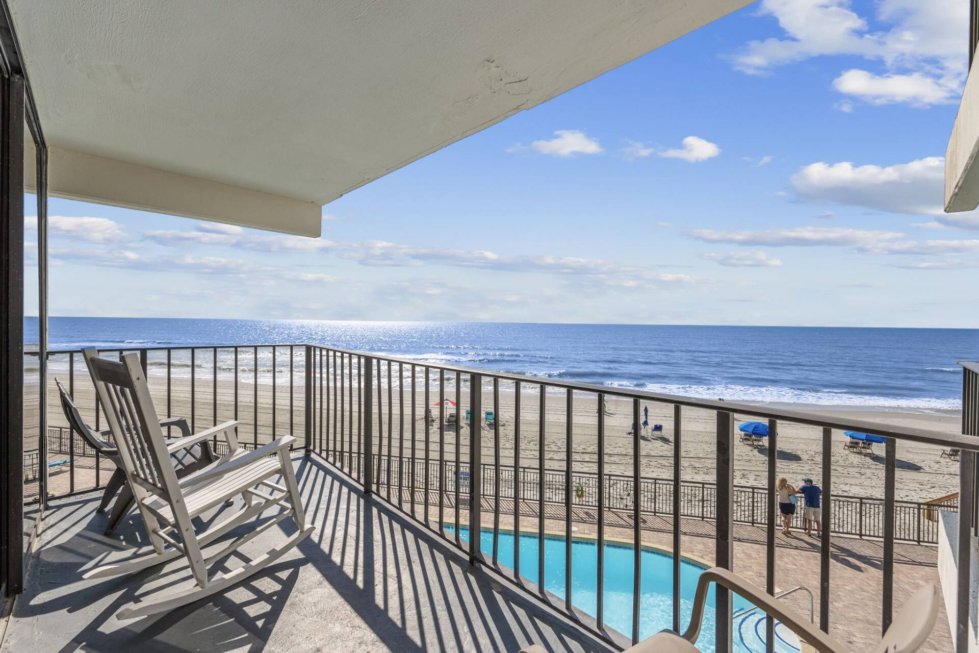 A balcony with a view of the beach and ocean.