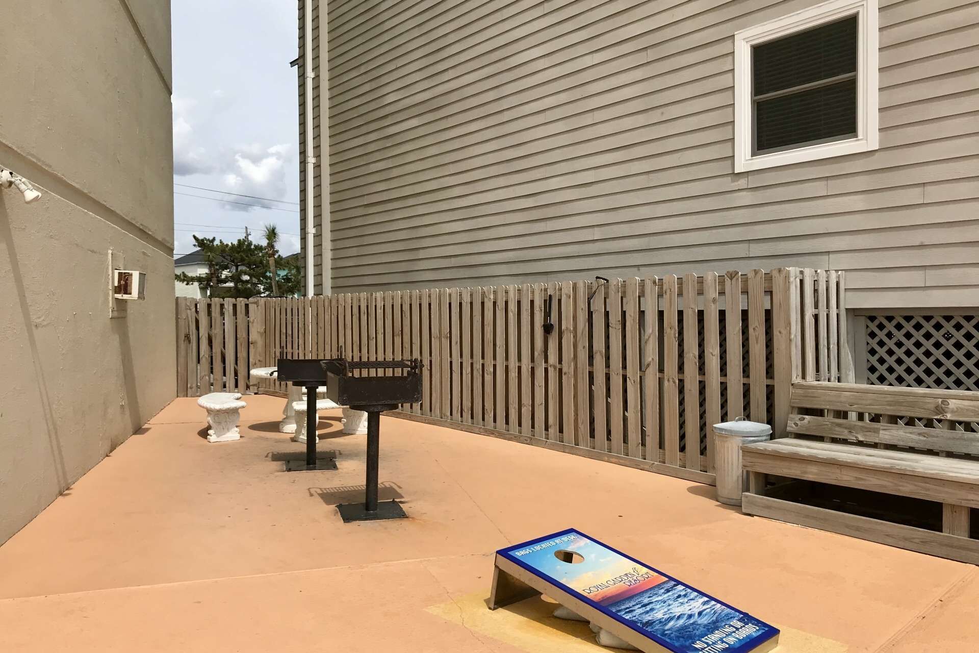 A patio area with a wooden fence, a barbecue grill, and outdoor seating.