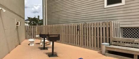 A patio area with a wooden fence, a barbecue grill, and outdoor seating.