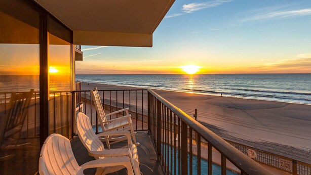 A balcony with a view of the sunset over the ocean, a pool, and beach chairs. - *Fall into Savings-20% Off New Bookings thru 2026* (Murrells Inlet)