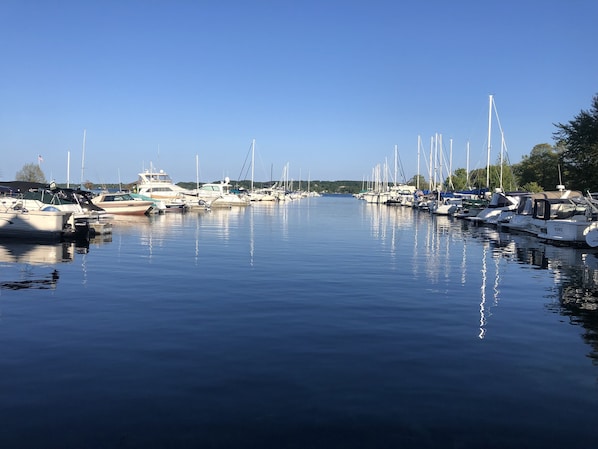 Un port de plaisance où sont amarrés différents types de bateaux, avec une eau calme et un ciel dégagé.