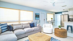 A modern living room with a grey sofa, a white armchair, and a woven coffee table.