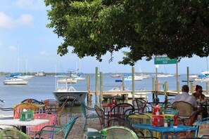 A waterfront restaurant with outdoor seating, a sign for Bridgetown Inn, and boats in the background.