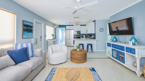 A living room with a sofa, a round wicker coffee table, and a TV on a cabinet.