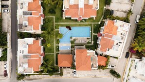 An aerial view of a residential area with multiple houses, a swimming pool, and a road. - Corte Sea C101_200Mbps_Pool_Gym_Walk to Beach! (Bavaro-Punta Cana)