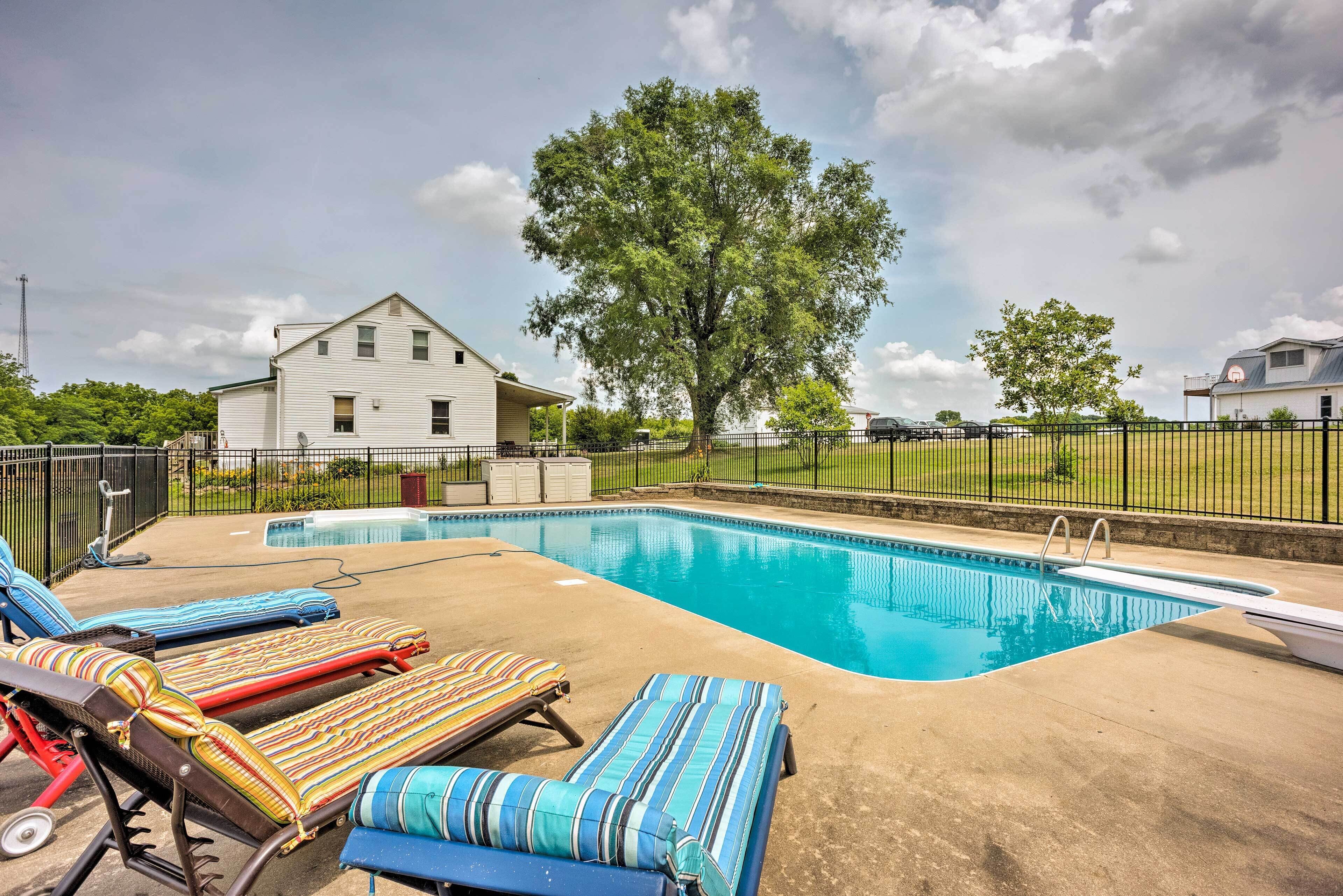 A swimming pool with lounge chairs and a house in the background.