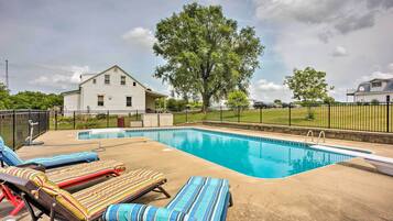 A swimming pool with lounge chairs and a house in the background.