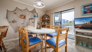 Comedor con una mesa redonda y sillas de madera, un candelabro y vista a la ciudad a través de un ventanal grande.