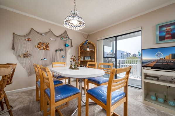 Un coin repas avec une table ronde et des chaises en bois, un lustre et une vue sur la ville par une grande fenêtre.