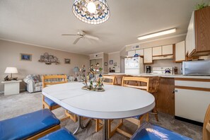 Une cuisine de taille réduite comprenant une table à manger, des chaises et un ventilateur de plafond.