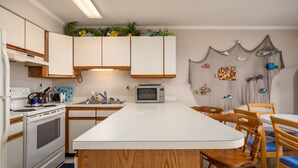 Una cocina con armarios blancos, microondas, estufa y una isla de madera.