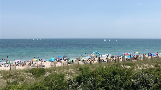 Una playa con varios sombrillas y gente.