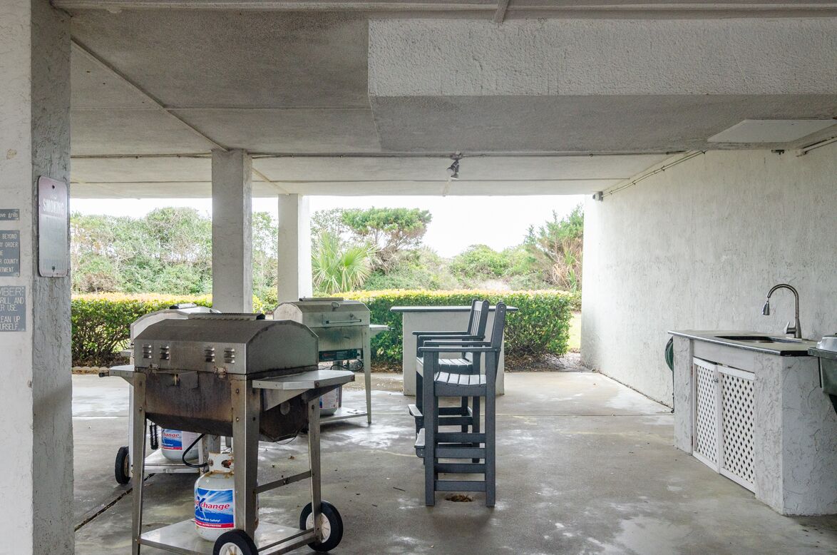 Une terrasse extérieure équipée d’un barbecue, d’un évier et d’une table avec des chaises.
