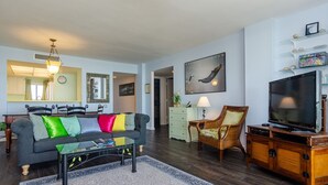 Una sala de estar con sofá, mesa de centro, televisor y objetos decorativos.