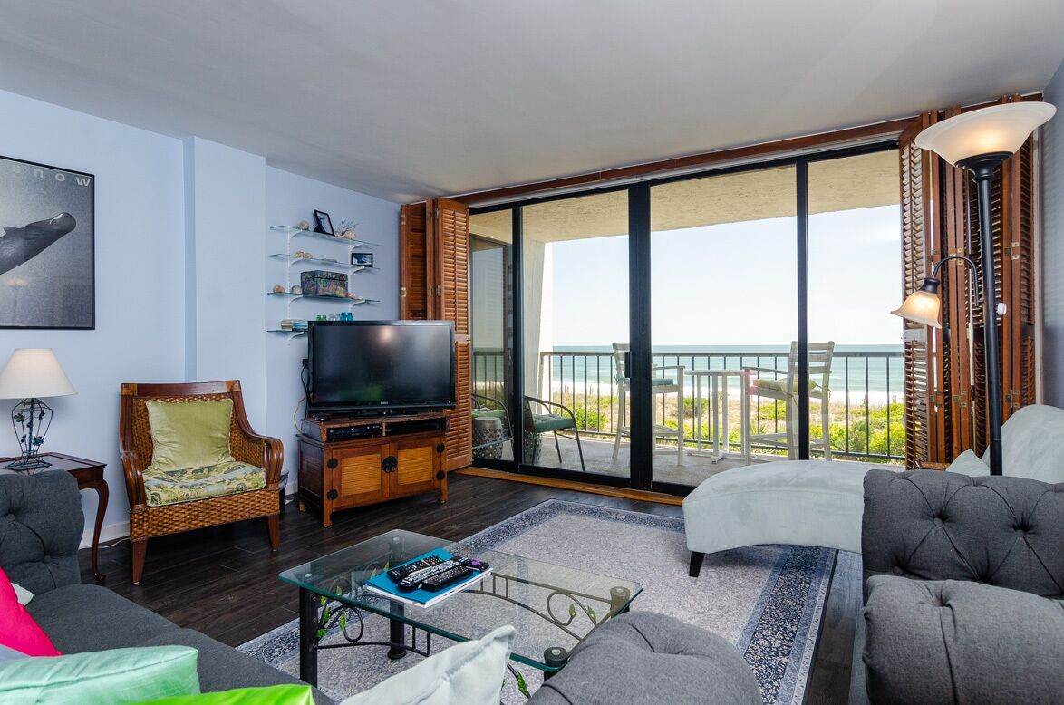 Un salón con televisor, asientos y un balcón con vistas.