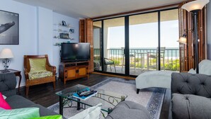 Un salón con televisor, asientos y un balcón con vistas.