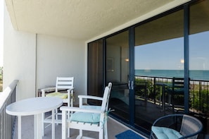 Enjoy the ocean view from this balcony with a table and two chairs.