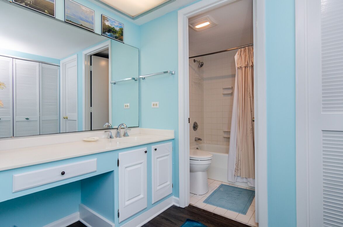 A bathroom with a white sink, a mirror, and a shower with a beige curtain.