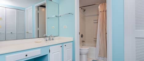 A bathroom with a white sink, a mirror, and a shower with a beige curtain.