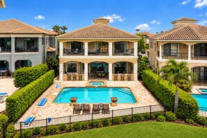 A two-story house with a swimming pool, outdoor seating, and a well-maintained garden.