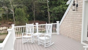 Une terrasse en bois avec des balustrades blanches et deux fauteuils à bascule.