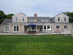 A two-story house with a covered patio area, a fenced deck, and a well-maintained lawn.