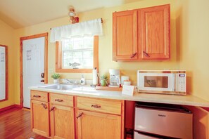 A kitchen with wooden cabinets, a white refrigerator, a microwave, and a sink. - 4 Mi to Museums: Cozy Branson Cabin (Branson)
