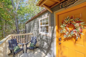 A wooden cabin with a porch, two Adirondack chairs, a welcome sign, and a wreath on the door. - 4 Mi to Museums: Cozy Branson Cabin (Branson)