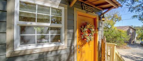 A wooden house with a yellow door, a welcome sign, and a wreath.