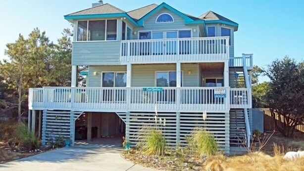 Ein zweigeschossiges Strandhaus mit Balkon, überdachter Eingangstür und sichtbarer Garage.