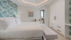 Ein modernes Hotelzimmer mit einem großen Bett, einem Kleiderschrank und Blick ins Freie.