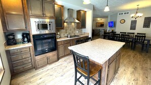 Una cocina con armarios de madera, electrodomésticos de acero inoxidable, una isla grande y una zona de comedor con sillas.