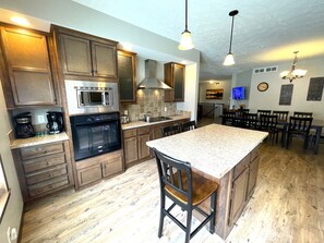 A kitchen with wooden cabinets, stainless steel appliances, a large island, and a dining area with chairs.