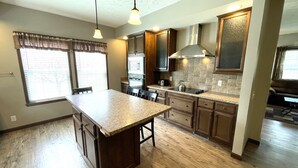 Una cocina con una isla central, armarios de madera y estufa empotrada.