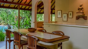 Un coin repas avec une table et des chaises en bois, un ventilateur de plafond et des tableaux encadrés accrochés au mur.