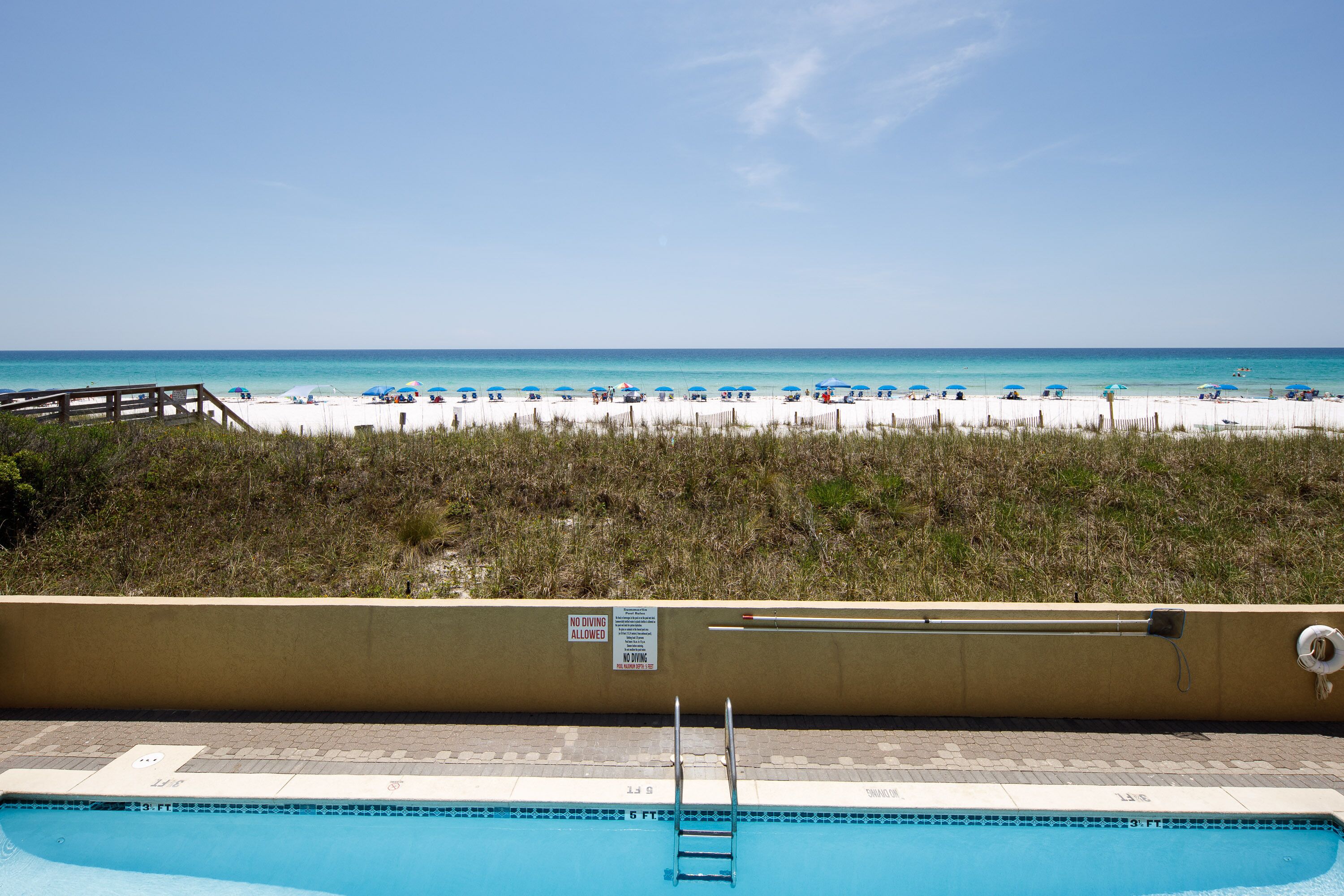 A pool with a wooden deck and a beach view.