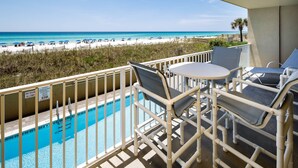 Un balcon avec piscine, vue sur la plage et espace salon extérieur.