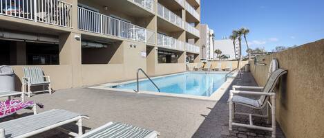 A pool area with lounge chairs and a swimming pool.