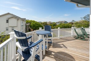 A wooden deck with outdoor furniture, a white fence, and houses in the background. - Blue Heron, Pet Friendly Corolla Home with Private Pool, Hot Tub and Ocean Views! (Corolla)